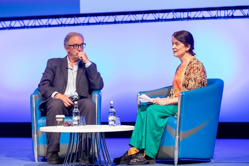 An on stage conversation with a male and female speaker seated at a small table